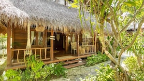 A wooden structure with a thatched roof, surrounded by lush greenery and a stone pathway. - Tigerlillys Boutique Hotel (Lembongan Island)