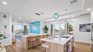 Una cocina moderna con una isla central, taburetes de bar y vistas al exterior.