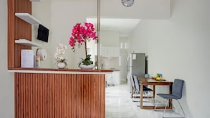 A modern kitchen with a wooden island, white cabinets, and a dining area with a table and chairs. - OYO 95054 Prima Jaya Homestay Syariah (Tawang)