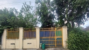 A gated entrance with a concrete wall, metal gate, and a trash bin. - OYO 95054 Prima Jaya Homestay Syariah (Tawang)