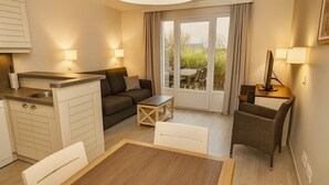 A compact living space with a kitchenette, a sofa, a dining table, and a chair. - Private House in the Normandy Garden – Pierre & Vacances Resort (Branville)