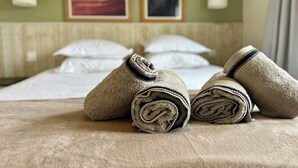 A hotel room with a neatly made bed, two framed pictures on the wall, and rolled towels on the bed. - Private House in the Normandy Garden – Pierre & Vacances Resort (Branville)