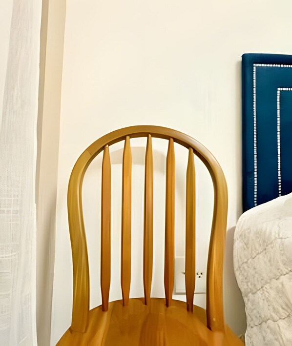 A wooden chair with a curved backrest and vertical slats, positioned against a white wall with a blue decorative panel.