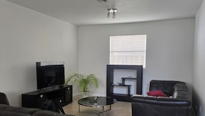 A living room with a sectional sofa, a flat-screen TV, a coffee table, and a fireplace.