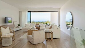 Una sala de estar moderna con un ventanal grande, muebles blancos y vistas al exterior.