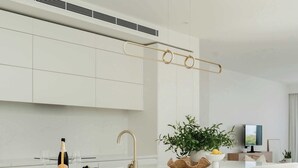 Una cocina moderna con una isla central, armarios blancos y piso de madera.