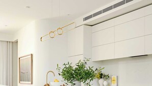 Una cocina moderna con una isla central, armarios blancos y piso de madera.