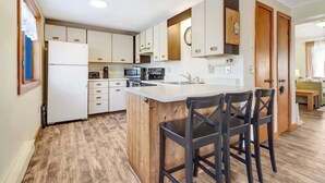 A modern kitchen with a central island, wooden cabinets, and a built-in microwave. - Crosstown Retreat | 2 Miles to Mt Snow w Fireplace (Dover)
