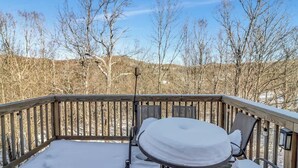 A snow-covered deck with a round table and chairs, surrounded by a wooden railing. - Crosstown Retreat | 2 Miles to Mt Snow w Fireplace (Dover)