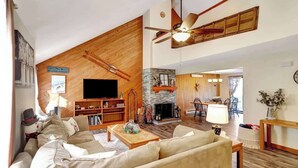 A spacious living room with a large TV, wooden accents, a fireplace, and a dining area. - Crosstown Retreat | 2 Miles to Mt Snow w Fireplace (Dover)