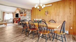 A dining area with a wooden table and chairs, a chandelier, and a sign on the wall. - Crosstown Retreat | 2 Miles to Mt Snow w Fireplace (Dover)