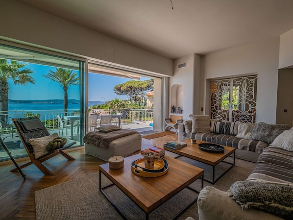 Ein geräumiges Wohnzimmer mit Meerblick, ein Balkon mit Gartenmöbeln und eine gemütliche Sitzecke.
