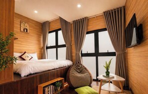 Een moderne slaapkamer met een bed, nachtkastje en een zithoekje met een plant.
