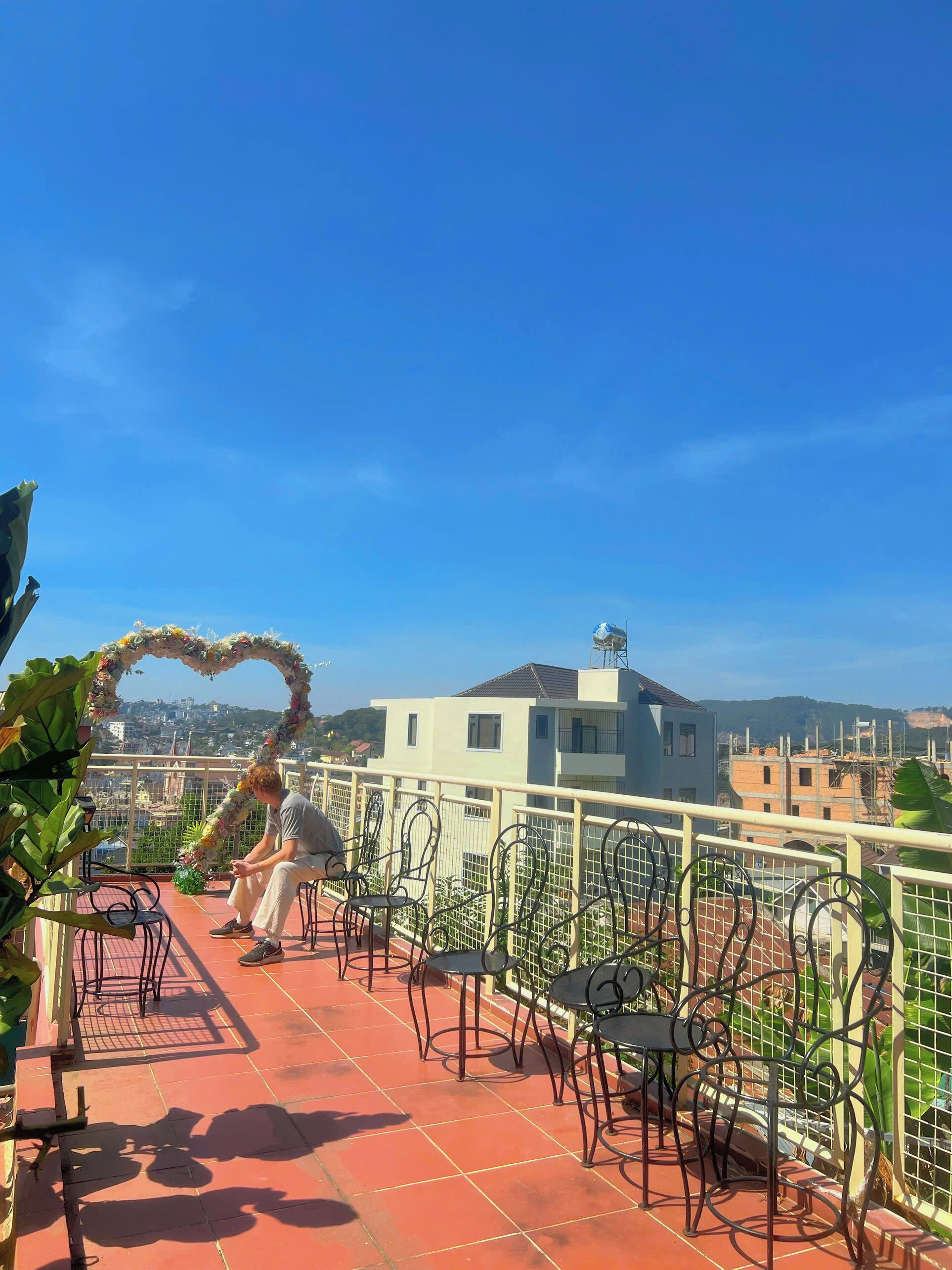 Terraza en la azotea con un arco floral con forma de corazón, sillas de metal y vistas a la ciudad.