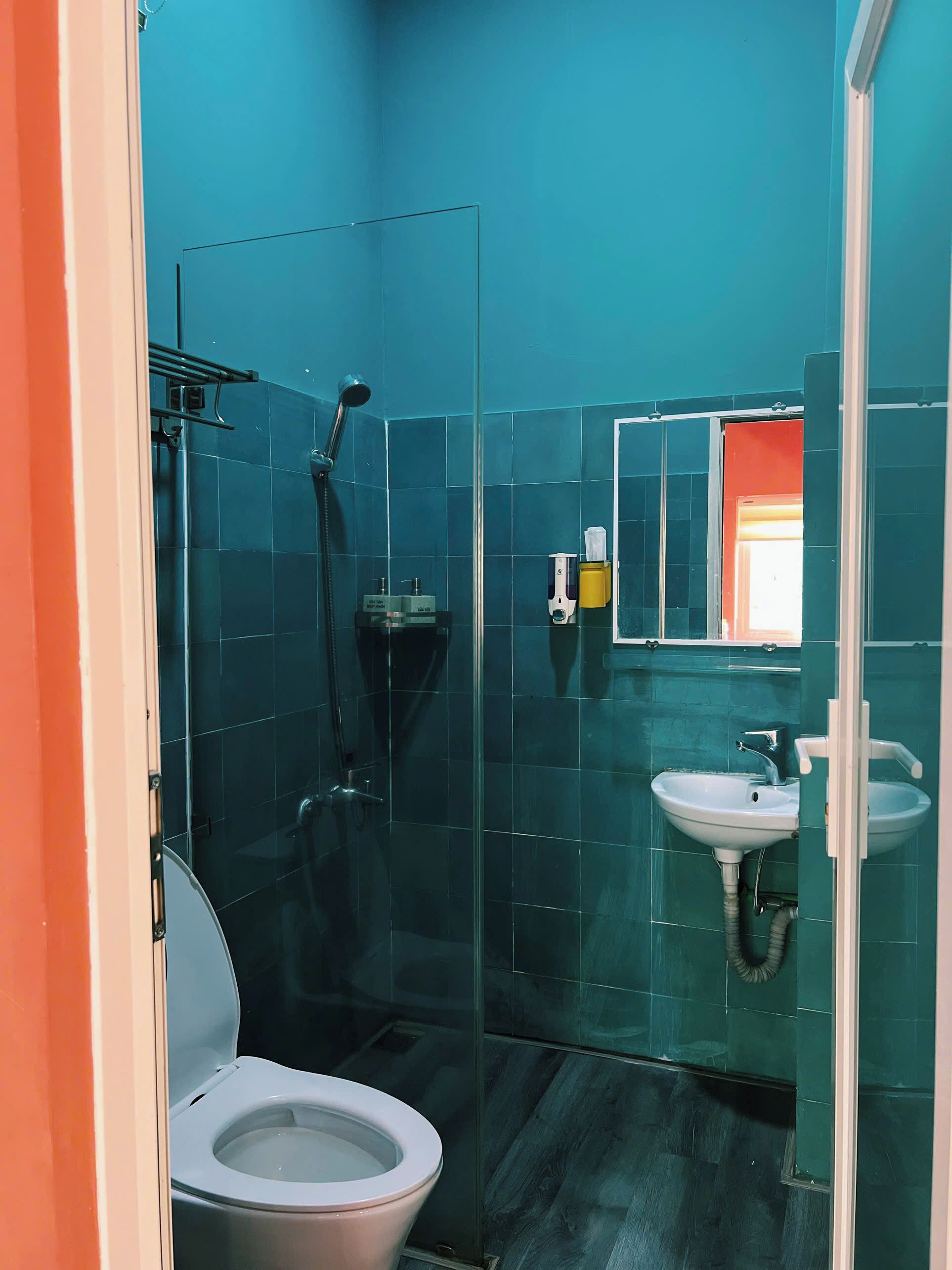 A bathroom with a glass shower enclosure, a white sink, and a toilet.