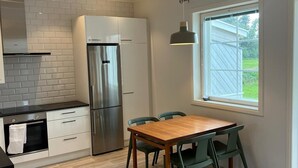 Eine moderne Küche mit einem Holzespeisetisch und Stühlen, einem eingebauten Backofen und einem großen Fenster mit Blick ins Freie.