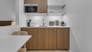 Une cuisine compacte dotée de meubles en bois, d’un four à micro-ondes, d’une machine à café et d’un évier.