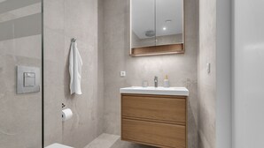 Une salle de bain moderne avec une douche à parois de verre, un meuble-lavabo en bois avec un miroir et des toilettes.