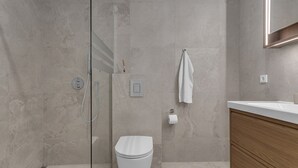 Une salle de bain moderne avec une douche à parois de verre, des toilettes et un meuble-lavabo en bois.