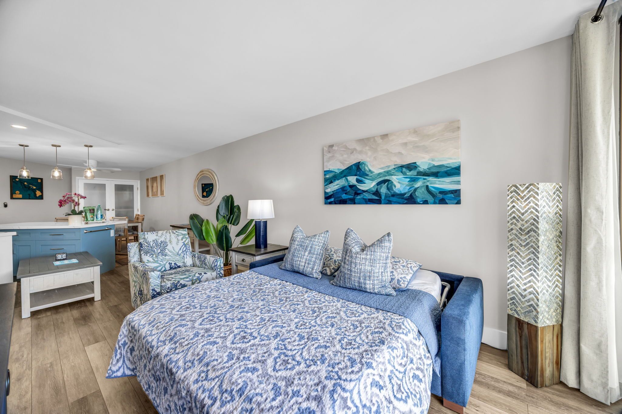 A modern bedroom with a large bed, a bedside table, a lamp, and a painting on the wall.