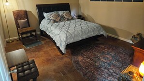 Une chambre à coucher avec un lit, une chaise, un tapis et une table de chevet avec une lampe.