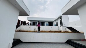 A modern building with a flat roof, a central staircase, and a group of people on the upper level. - Pearl Pride Villa (Udaipur)