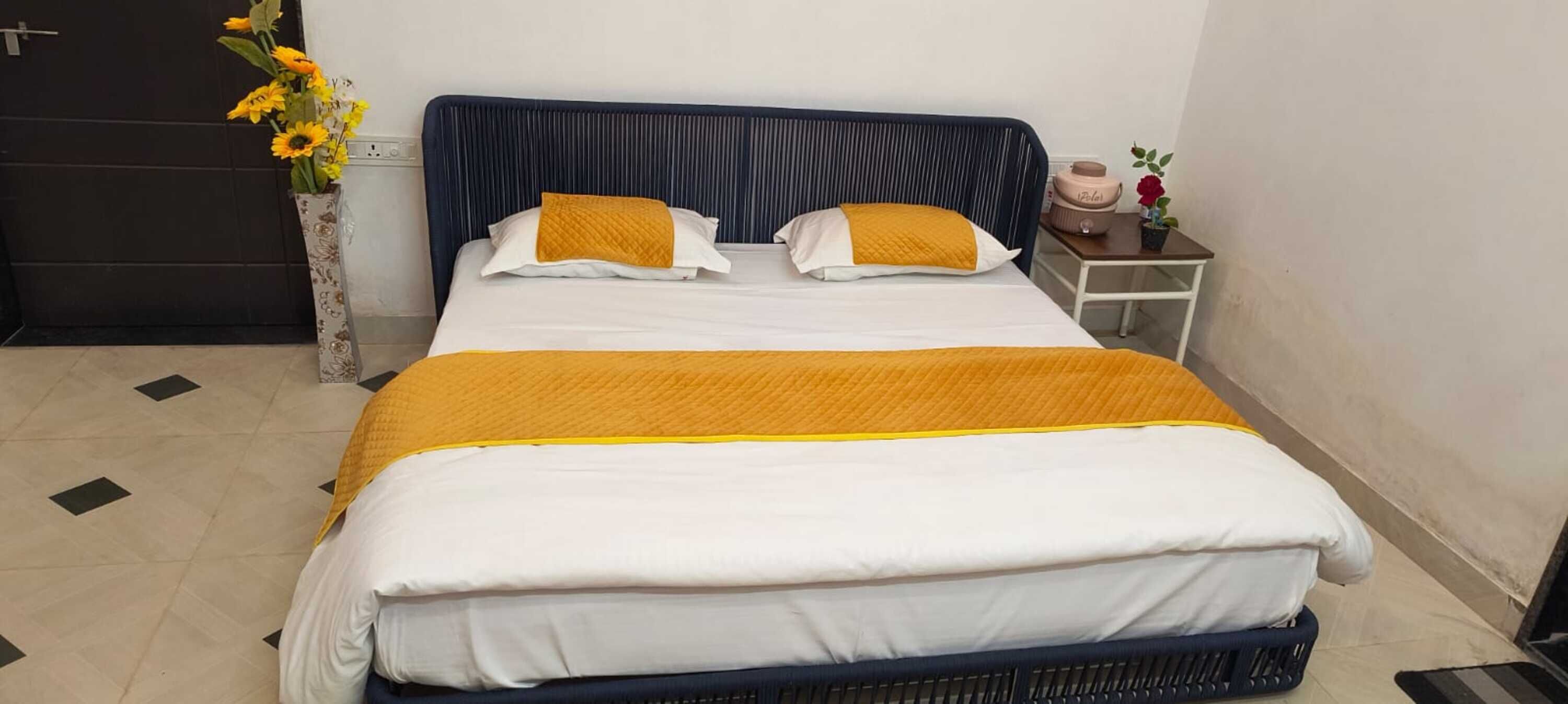 Una cama con cabecera azul, ropa de cama blanca y una manta amarilla.