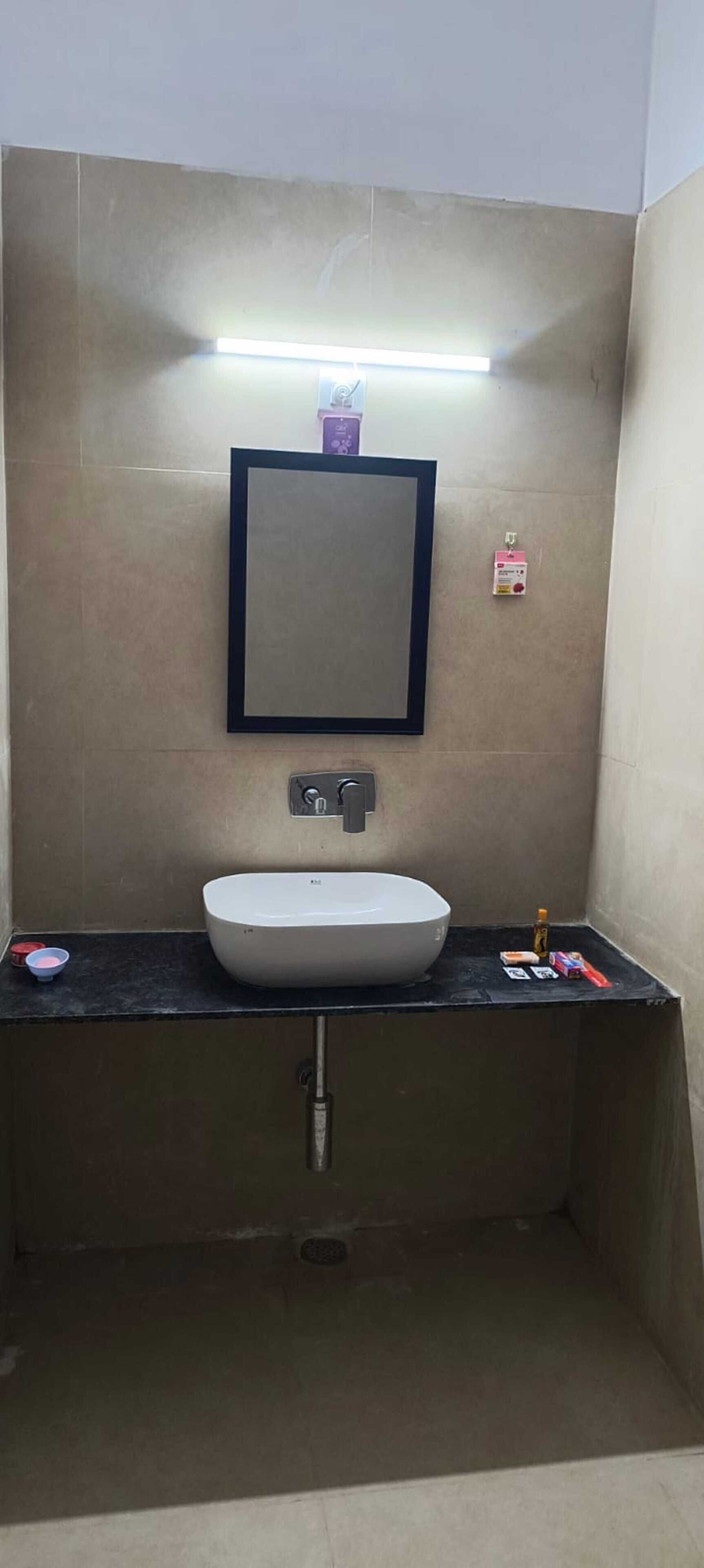 Een badkamer met een wit wastafel, een spiegel en een zwart aanrecht.