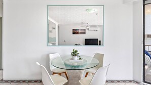 Un comedor moderno con una mesa de vidrio, sillas blancas y una planta en maceta.