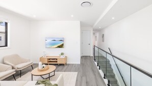Una sala de estar moderna con un sofá, una mesa de centro y un televisor montado en la pared.