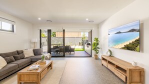 Una sala de estar moderna con un sofá, una mesa de centro y un cuadro de una playa.