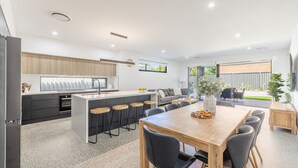Una cocina moderna con una isla central, taburetes de bar y un comedor con mesa y sillas de madera.
