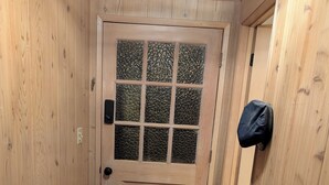 Eine Holztür mit Glasschiebeverglasung und einem Kreuzmuster, ein sechseckiger Fliesenboden und ein Rucksack an der Wand.