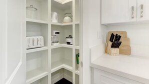 Eine weiße Küche mit weißen Schränken, einer Kaffeemaschine, einem Toaster und einem Messerblock.