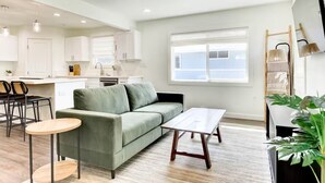 Ein modernes Wohnzimmer mit einem grünen Sofa, einem Holztisch und einem Essbereich mit Stühlen und einem kleinen Tisch.