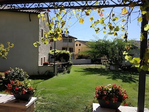 A courtyard with a well-maintained lawn, potted plants, and a stone wall. - Prosecco Hills Holidays: elegante abitazione per gruppi e famiglie (Miane)