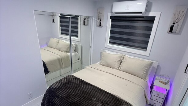 A bedroom with a bed, a bedside table, a mirror, and a window with blinds. - Comfort, location and a fair price, ALL IN ONE PLACE (Las Vegas)