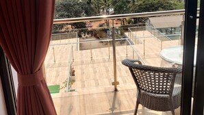 Un balcone con una sedia in vimini, vista sulla spiaggia e cielo sereno.
