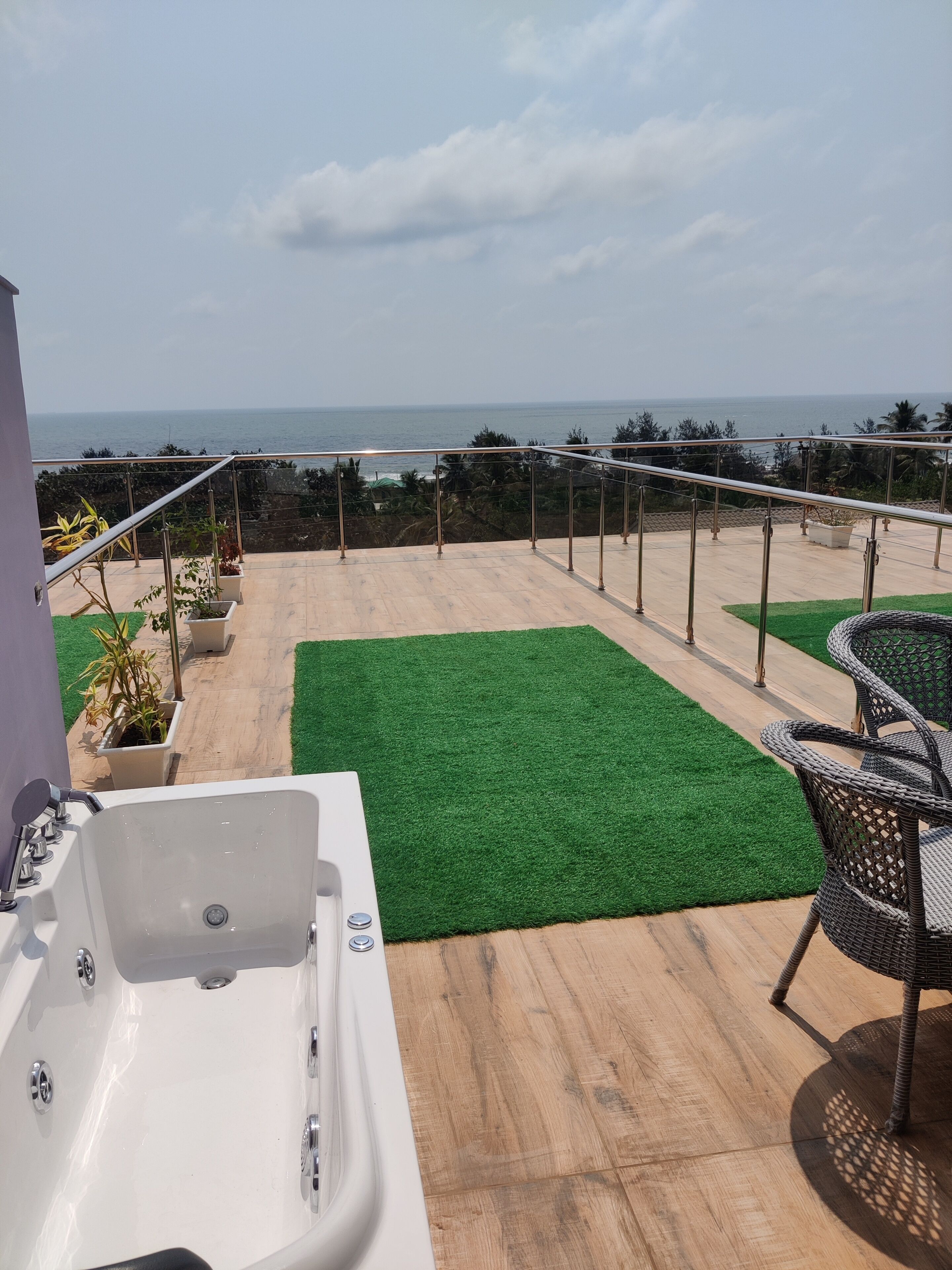 A rooftop terrace with a view of the sea, a jacuzzi, and outdoor furniture.