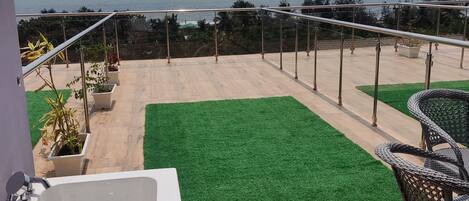 A rooftop terrace with a view of the sea, a jacuzzi, and outdoor furniture.