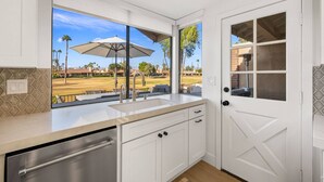 Una cocina con vista a un campo de golf, una ventana con paraguas y una puerta con ventana.