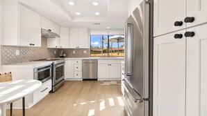 Una cocina moderna con armarios blancos, electrodomésticos de acero inoxidable y vistas a una zona turística.