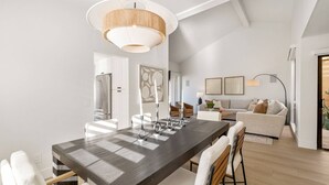 Una cocina moderna con una isla grande, muebles blancos y electrodomésticos de acero inoxidable.