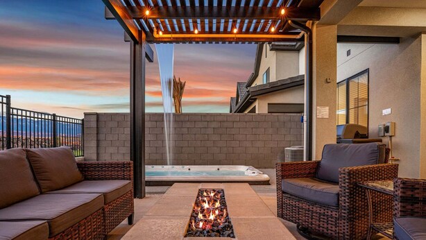 Un patio con mobiliario exterior, jacuzzi, chimenea y una cascada.