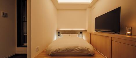 A modern bedroom with a skylight, a flat-screen TV, and a minimalist design.