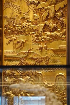 A detailed golden relief sculpture depicting a scene with birds, boats, and foliage. - CANTON HOTEL BEIJING (Beijing)