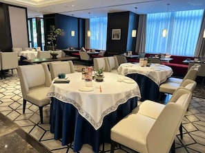 A dining area with round tables, white chairs, and blue curtains. - CANTON HOTEL BEIJING (Beijing)