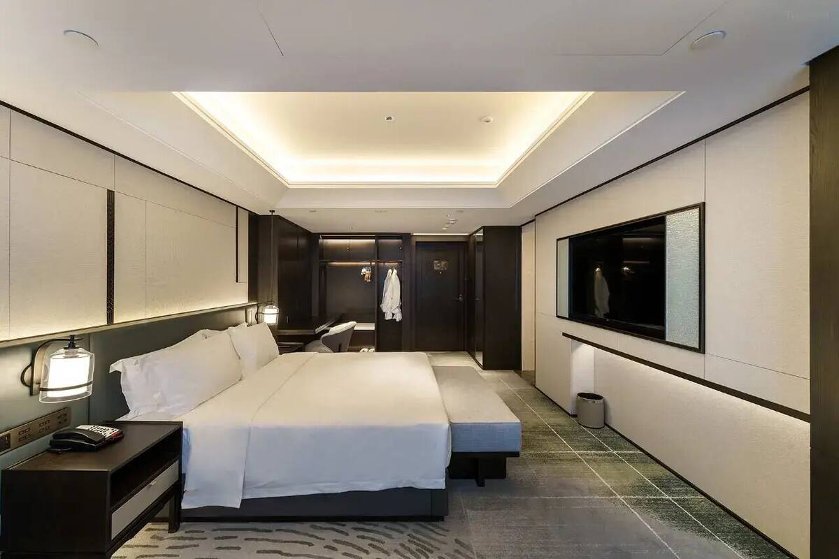 Ett modernt hotellrum med en stor säng, sängbord, en TV och en rymlig klädkammare.