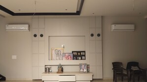 Ein Zimmer mit integriertem Unterhaltungseinbau, Klimaanlage und einer Sitzecke mit zwei Sesseln.
