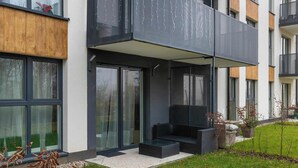 En modern byggnad med stora fönster, en takförsedd uteservering och en välskött gräsmatta.